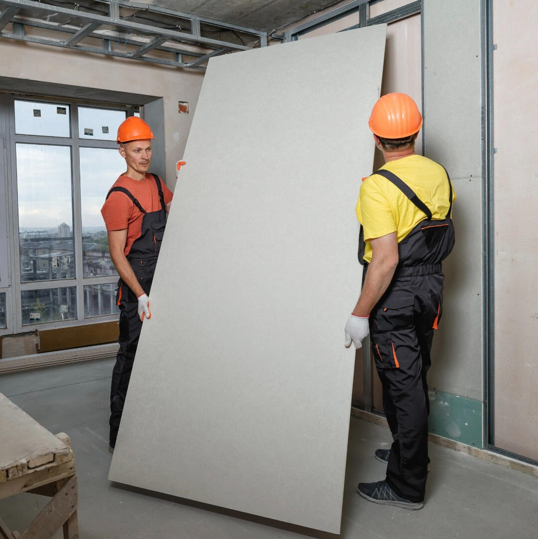 Zwei Männer tragen eine Trockenbauwand